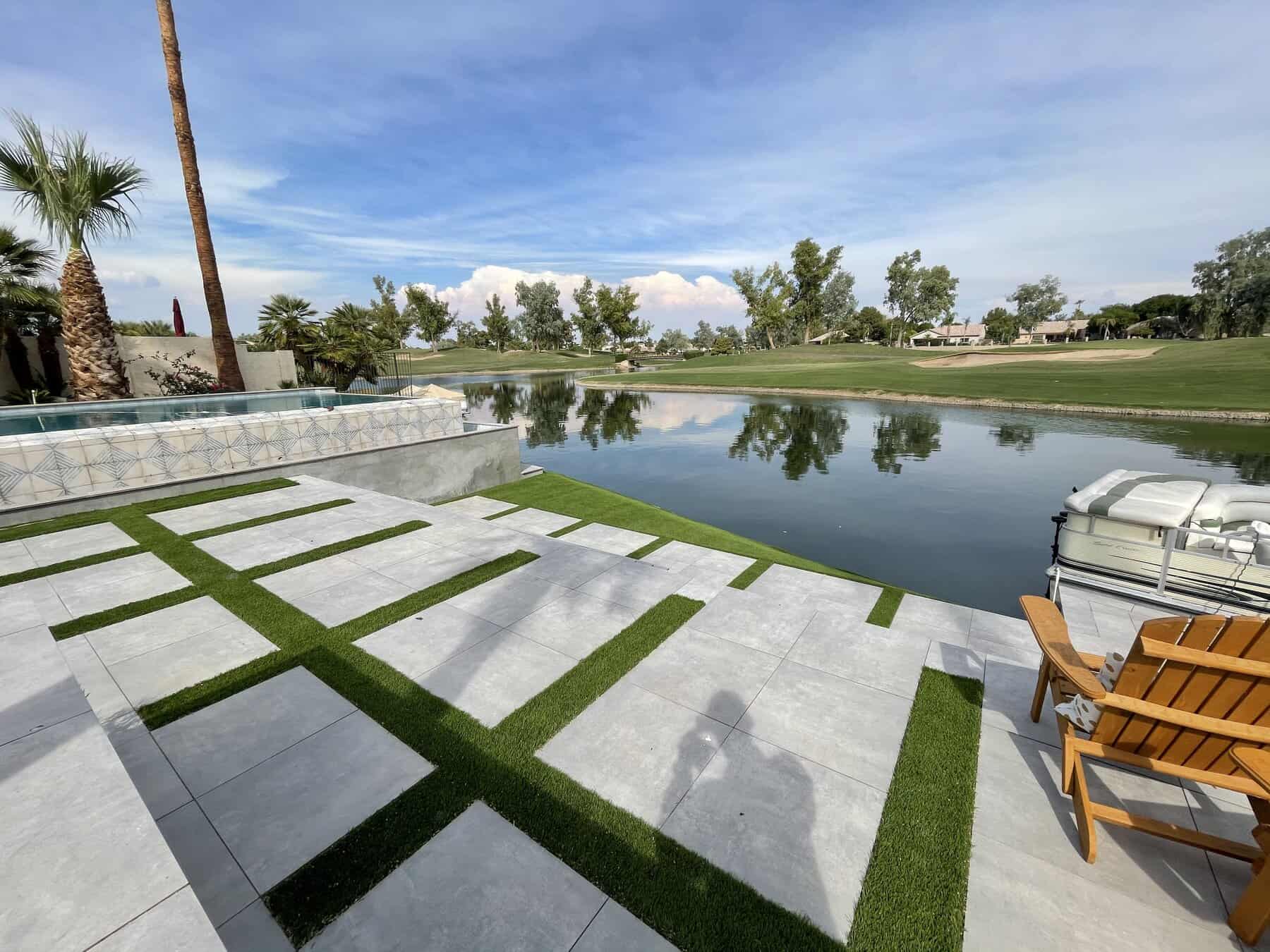 Aerial view of a large, modern white house with a circular swimming pool in the backyard, beautiful pavers installed by a top Pavers Installer Texas, surrounded by mountains, desert landscaping, and patches of green lawn.